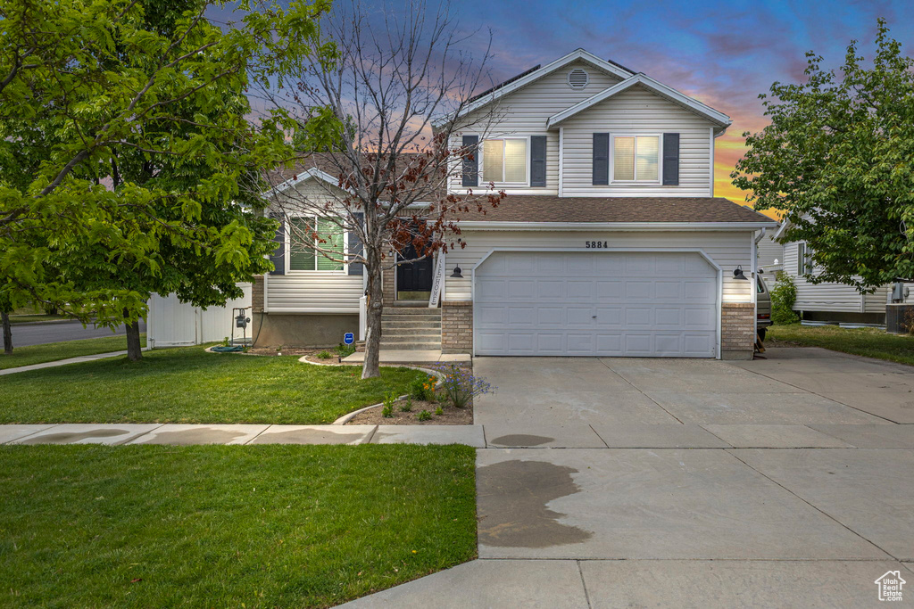View of front of property with a garage, driveway, a front yard, and brick siding