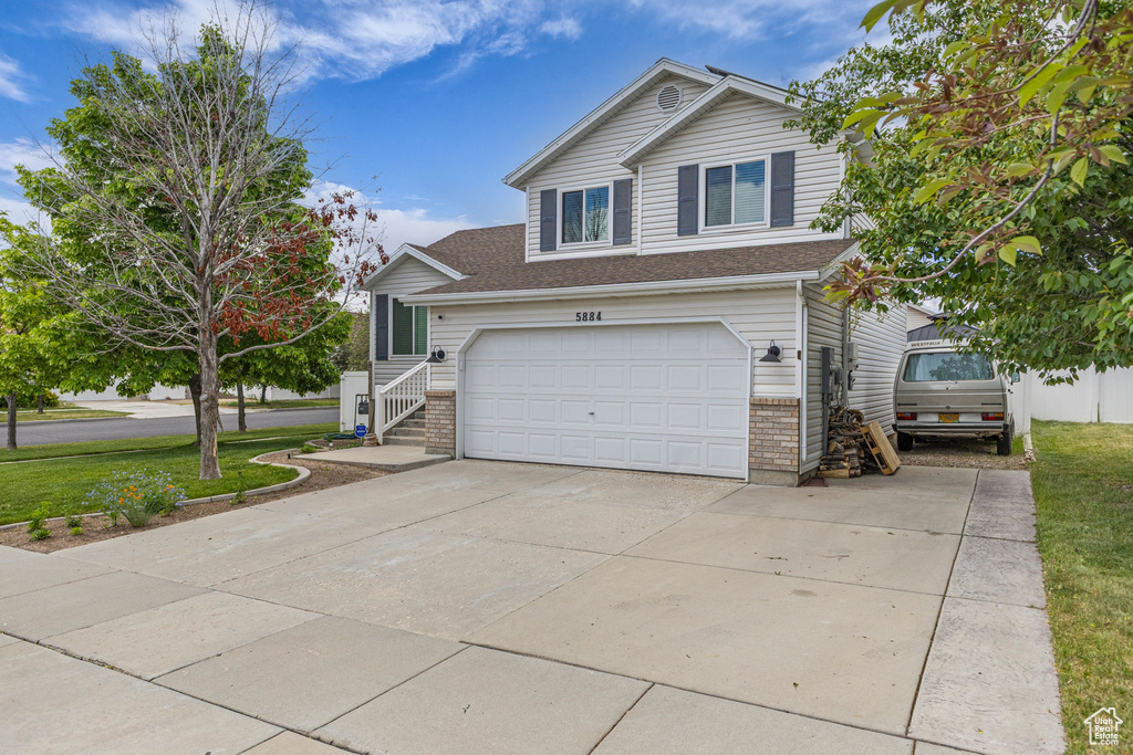 Traditional home featuring driveway, an attached garage, a front lawn, and brick siding