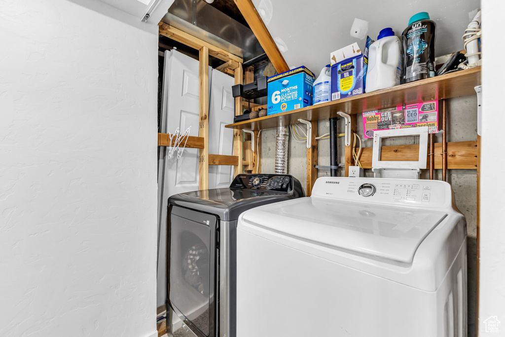 Clothes washing area featuring washer and dryer and a textured wall
