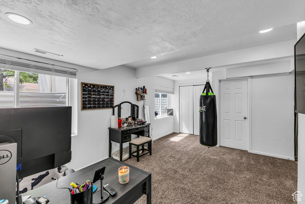Carpeted living area with a textured ceiling, recessed lighting, and baseboards