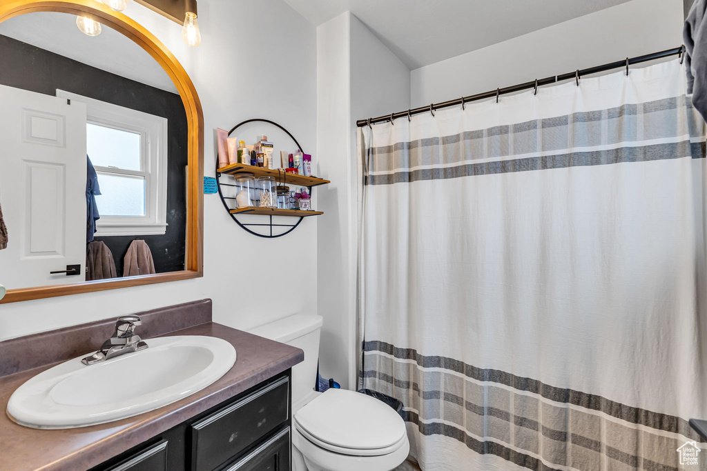 Full bathroom featuring toilet, vanity, and curtained shower