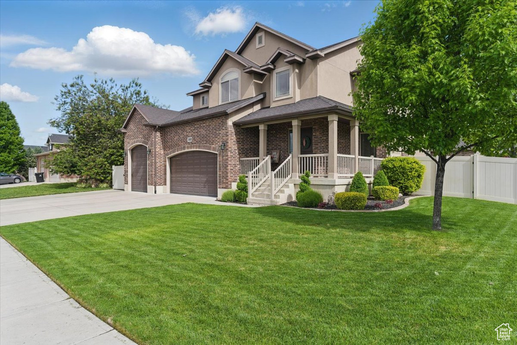 View of front of house with driveway, brick siding, stucco siding, a porch, and a garage