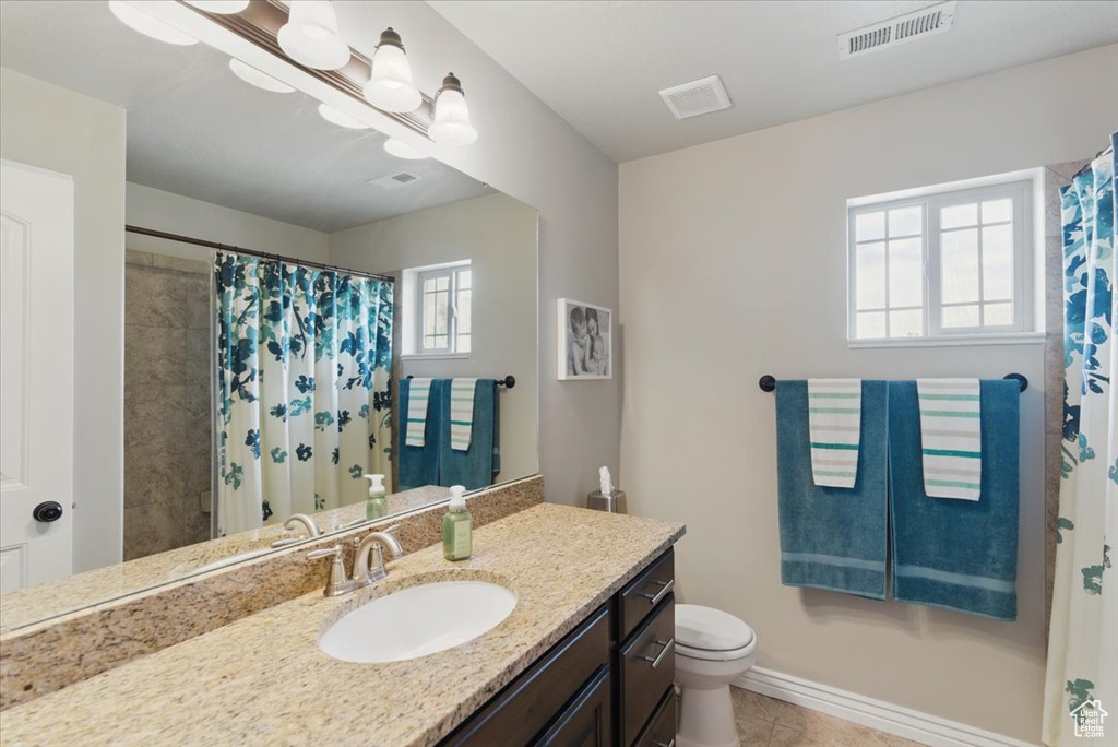 Bathroom with toilet, vanity, tile patterned flooring, curtained shower, and baseboards