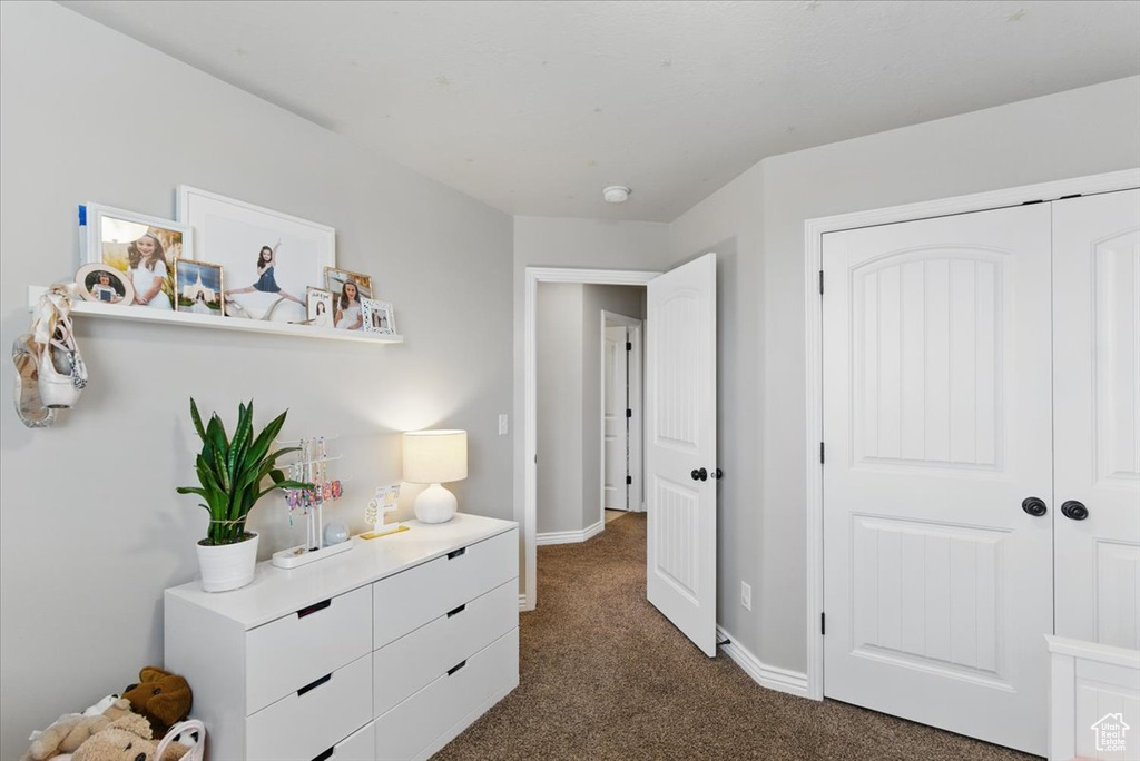 Bedroom featuring dark colored carpet, baseboards, and a closet