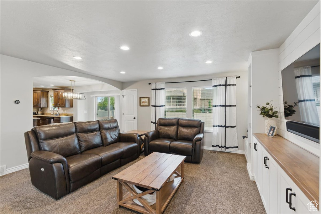 Living room with light colored carpet, arched walkways, recessed lighting, baseboards, and a textured ceiling