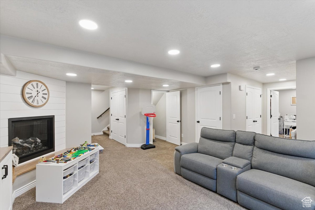 Living area featuring light colored carpet, recessed lighting, a fireplace, baseboards, and stairway