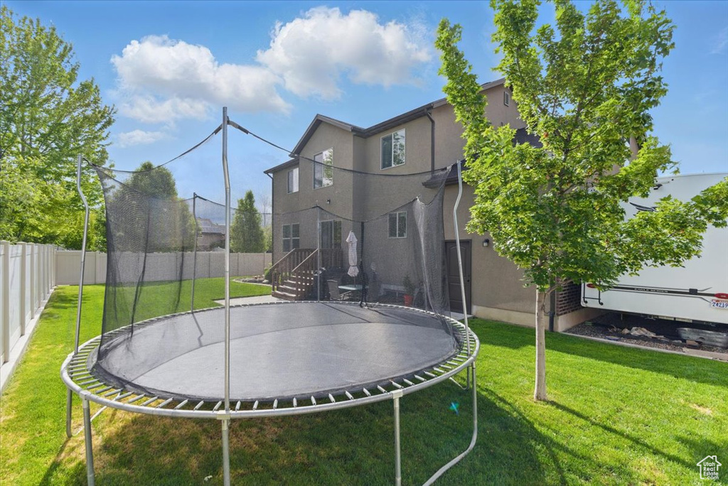 Back of property featuring a trampoline and stucco siding