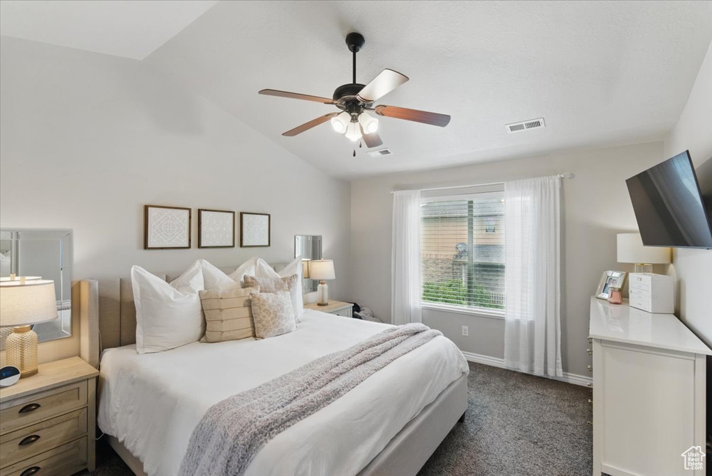 Bedroom featuring vaulted ceiling, baseboards, dark colored carpet, and ceiling fan