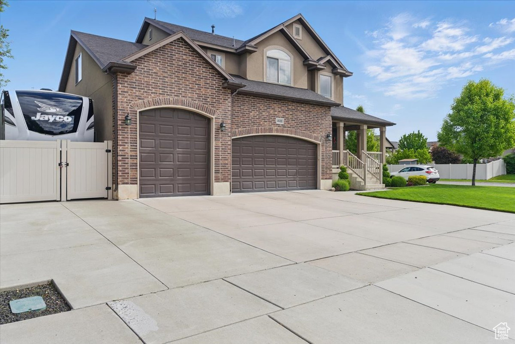 View of front of property with brick siding, concrete driveway, stucco siding, a gate, and a shingled roof