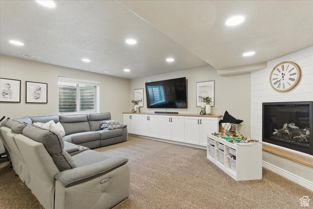Living room with light carpet, recessed lighting, and a fireplace