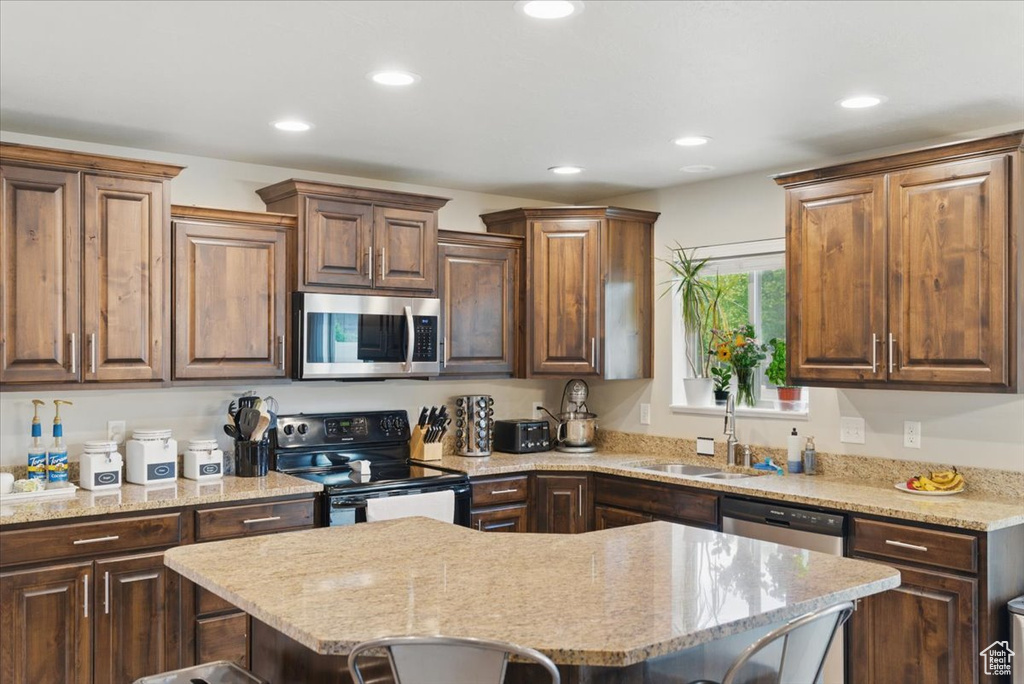 Kitchen featuring appliances with stainless steel finishes, recessed lighting, a sink, a center island, and a kitchen breakfast bar