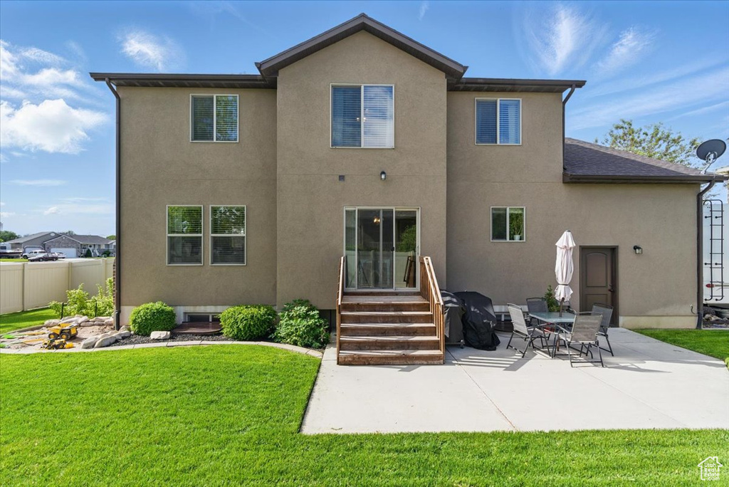 Rear view of house with stucco siding, a patio area, and entry steps