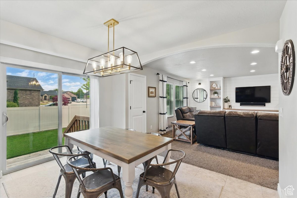 Dining space with recessed lighting, a chandelier, arched walkways, light tile patterned floors, and light carpet
