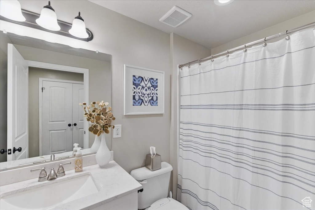 Full bathroom with toilet, vanity, and curtained shower