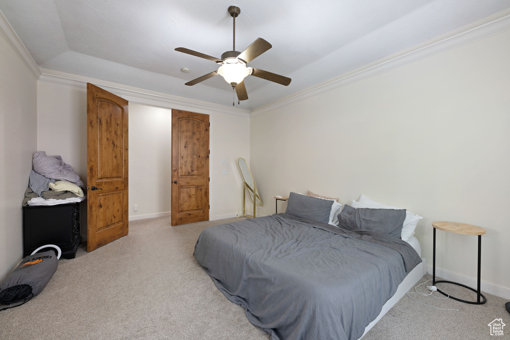Carpeted bedroom with baseboards, crown molding, and a ceiling fan