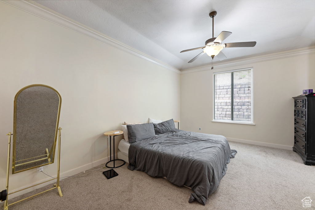 Bedroom featuring light colored carpet, ornamental molding, baseboards, and ceiling fan