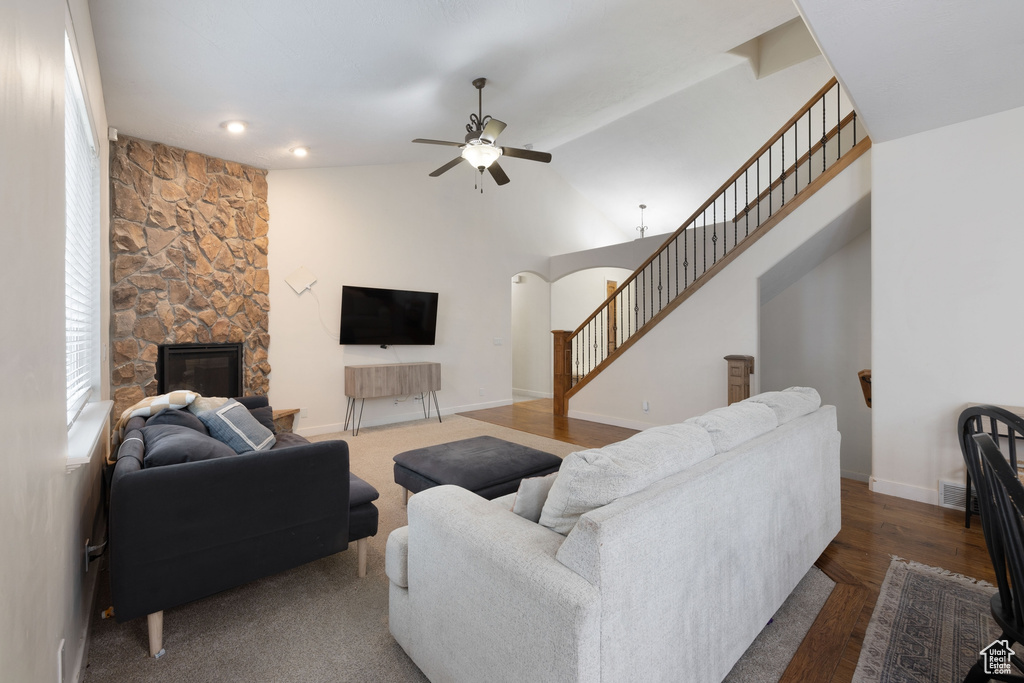 Living room with ceiling fan, stairs, a fireplace, arched walkways, and baseboards