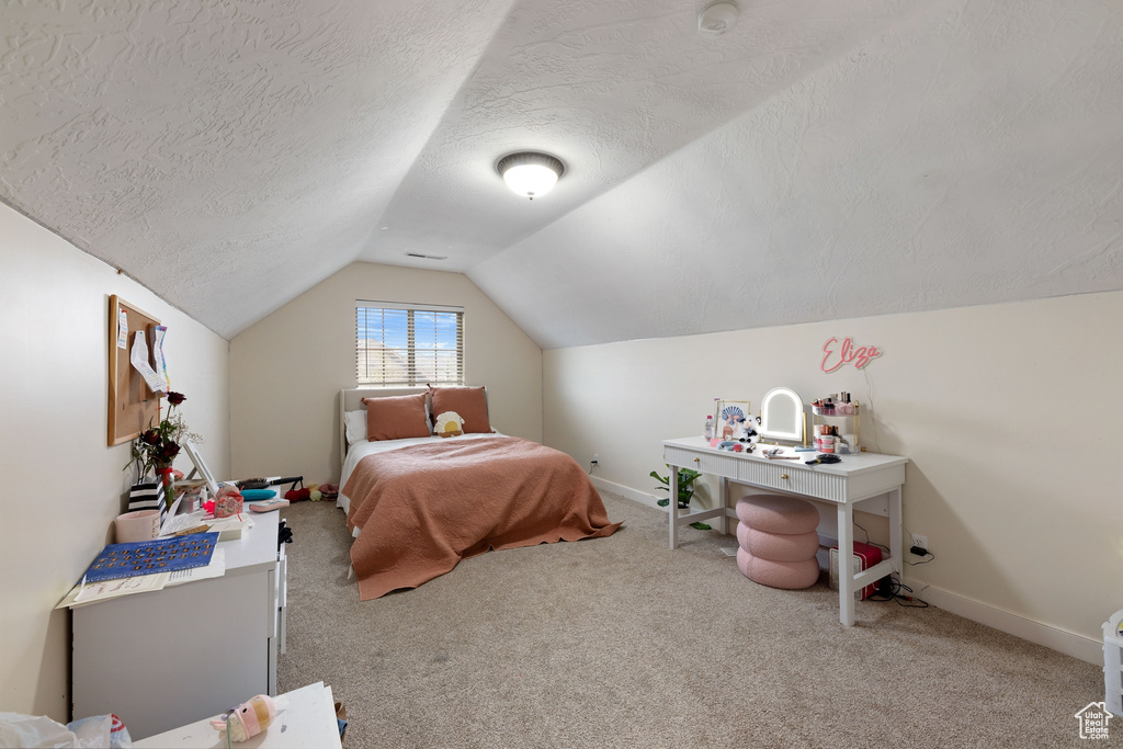 Carpeted bedroom featuring vaulted ceiling, baseboards, and a textured ceiling