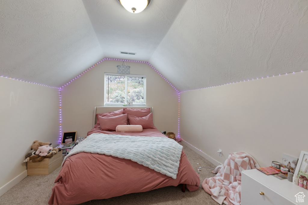 Carpeted bedroom with vaulted ceiling and baseboards