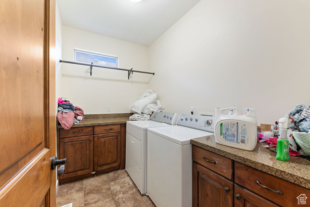 Clothes washing area featuring washer and clothes dryer and cabinet space