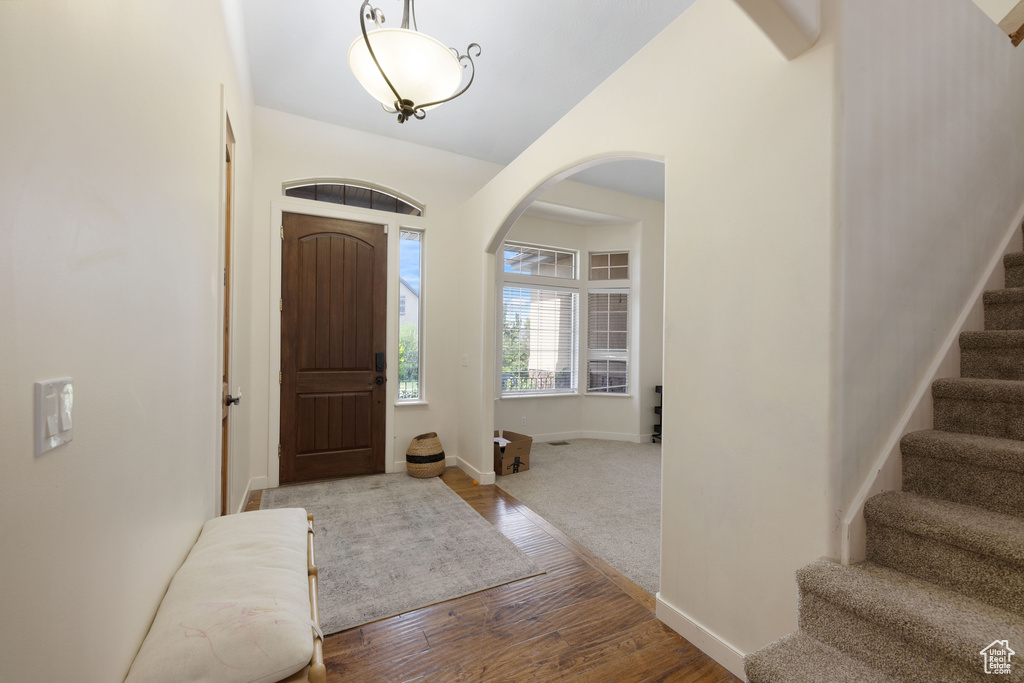 Entryway featuring arched walkways, stairs, wood finished floors, and baseboards
