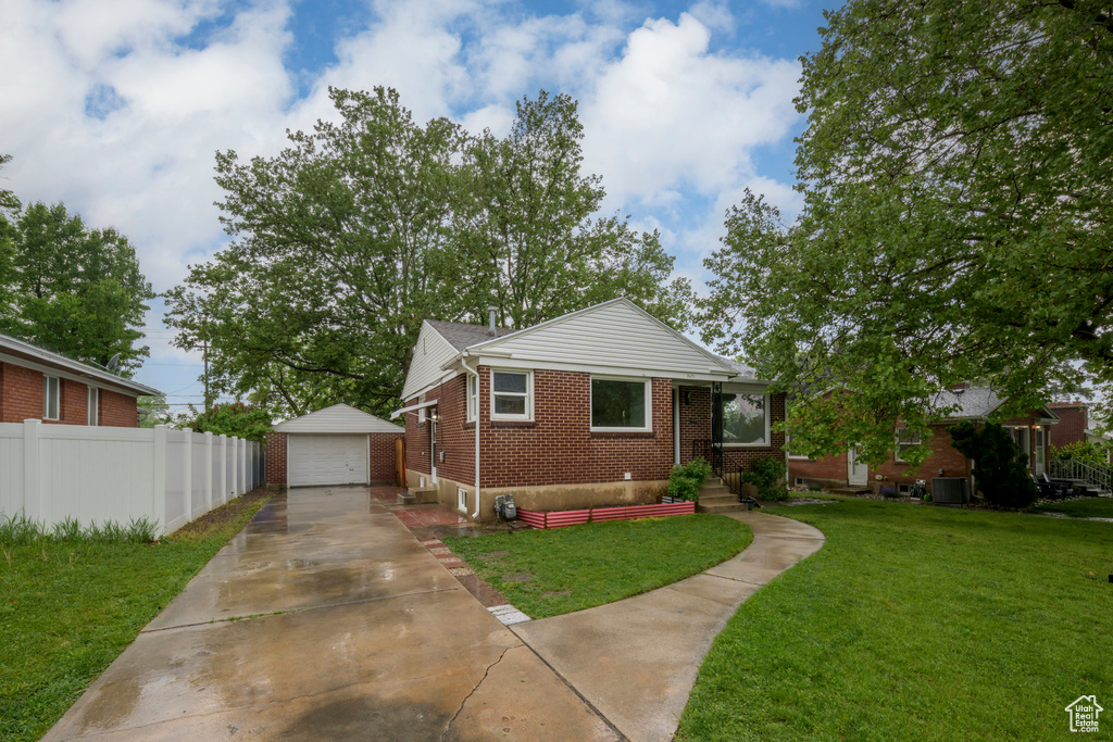 Bungalow-style house featuring brick siding, driveway, an outbuilding, and a detached garage