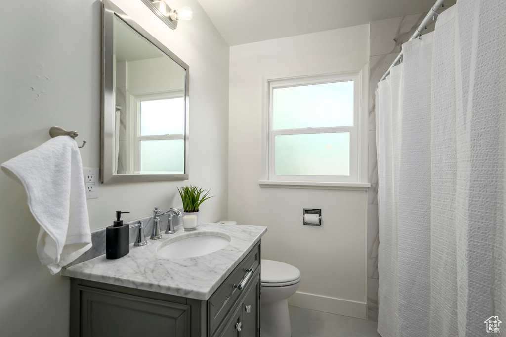 Bathroom featuring vanity, toilet, and baseboards