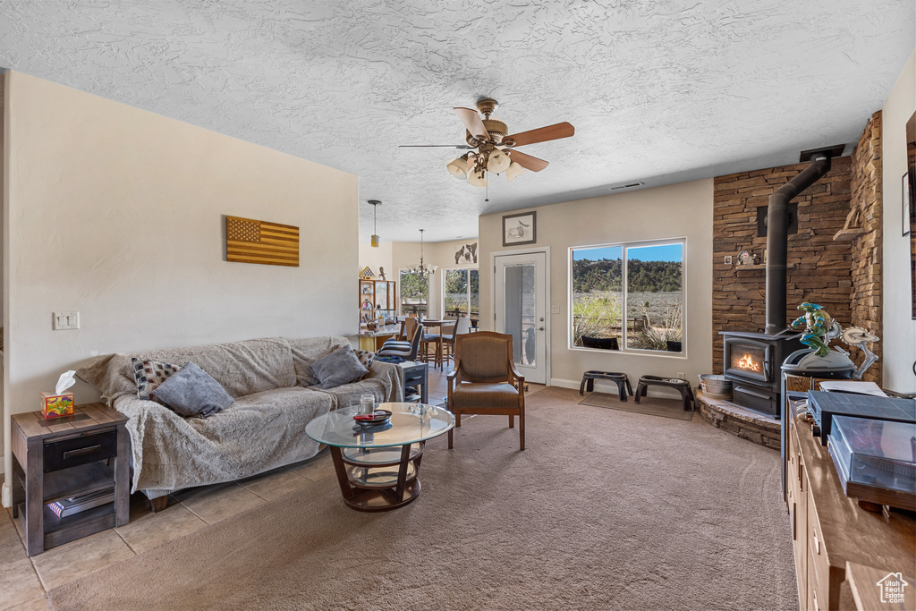 Living room featuring a wood stove, a ceiling fan, and a textured ceiling