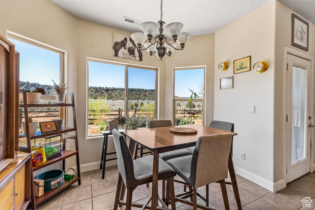 Dining space with a chandelier, light tile patterned floors, baseboards, and a textured ceiling