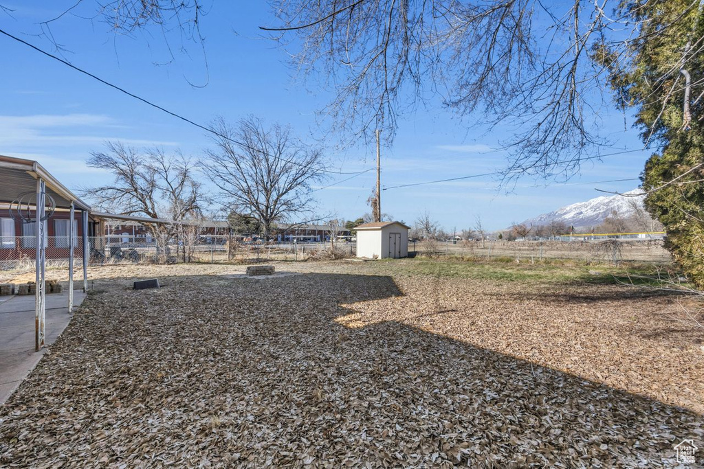 View of yard featuring a storage shed, fence, an outdoor structure, and a mountain view