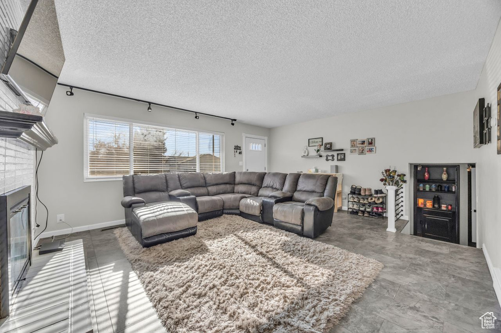 Living room with a textured ceiling, a brick fireplace, and baseboards