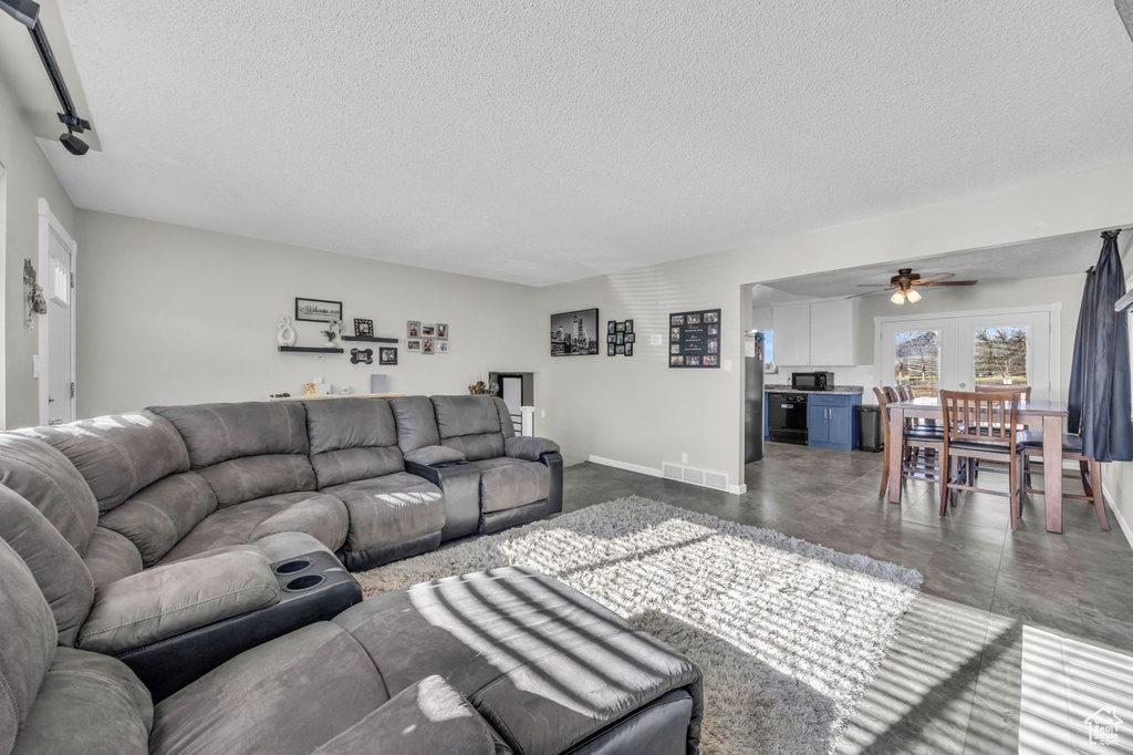 Living room featuring a textured ceiling, a ceiling fan, and baseboards