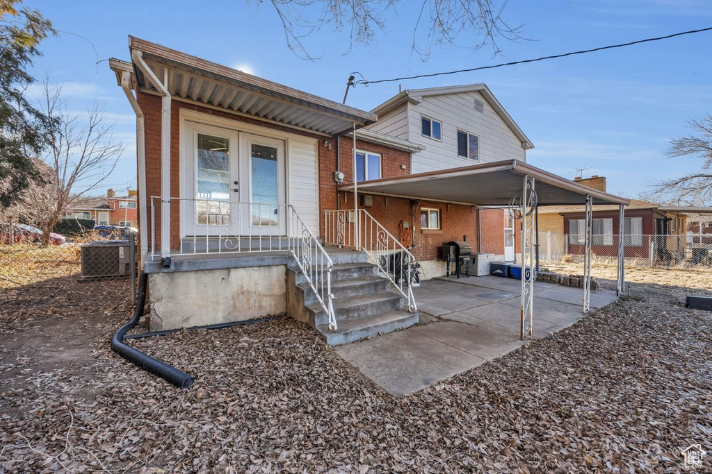 Rear view of property featuring fence, an attached carport, brick siding, and central AC