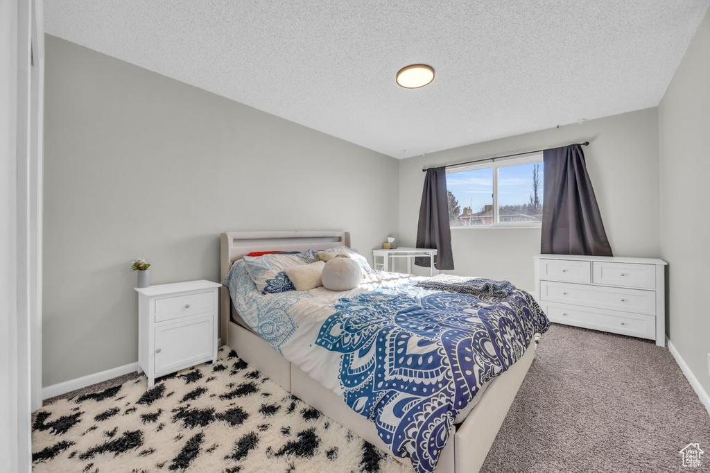 Bedroom with carpet floors, a textured ceiling, and baseboards