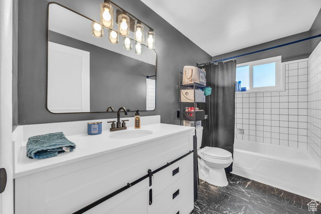 Bathroom featuring toilet, marble finish floors, vanity, and shower / bath combo