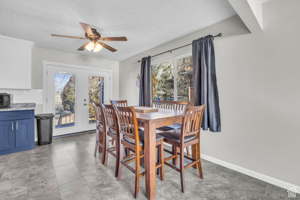 Dining area with french doors, ceiling fan, a textured ceiling, and baseboards