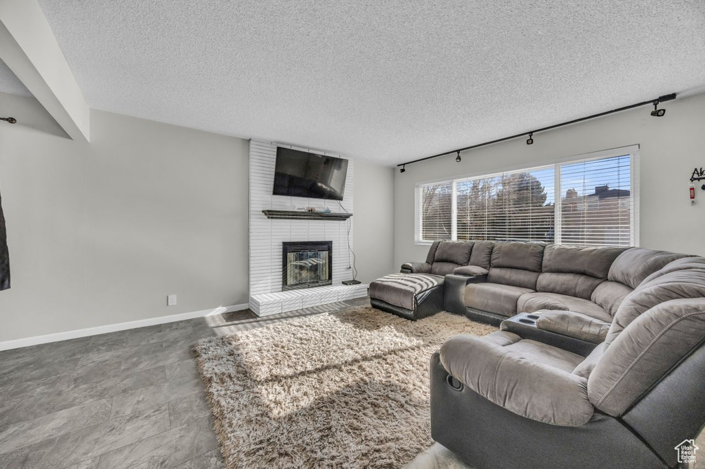 Living room featuring a textured ceiling, a brick fireplace, and baseboards
