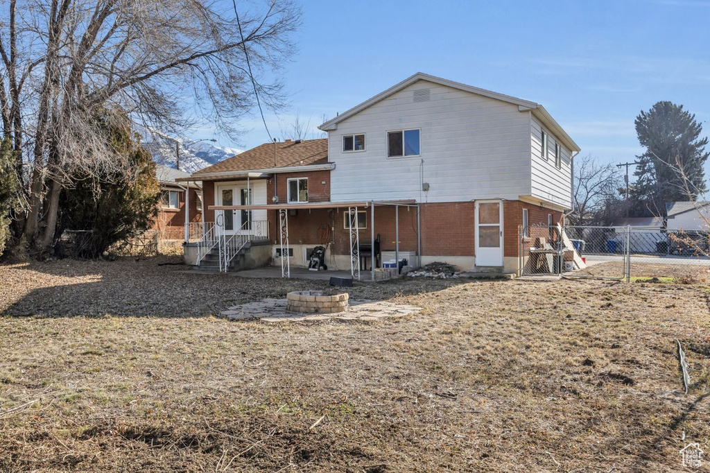 Rear view of house featuring brick siding, fence, and a patio