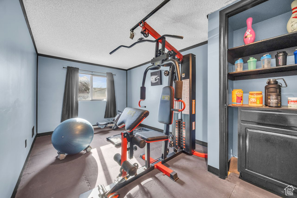 Workout area featuring a textured ceiling, baseboards, and ornamental molding