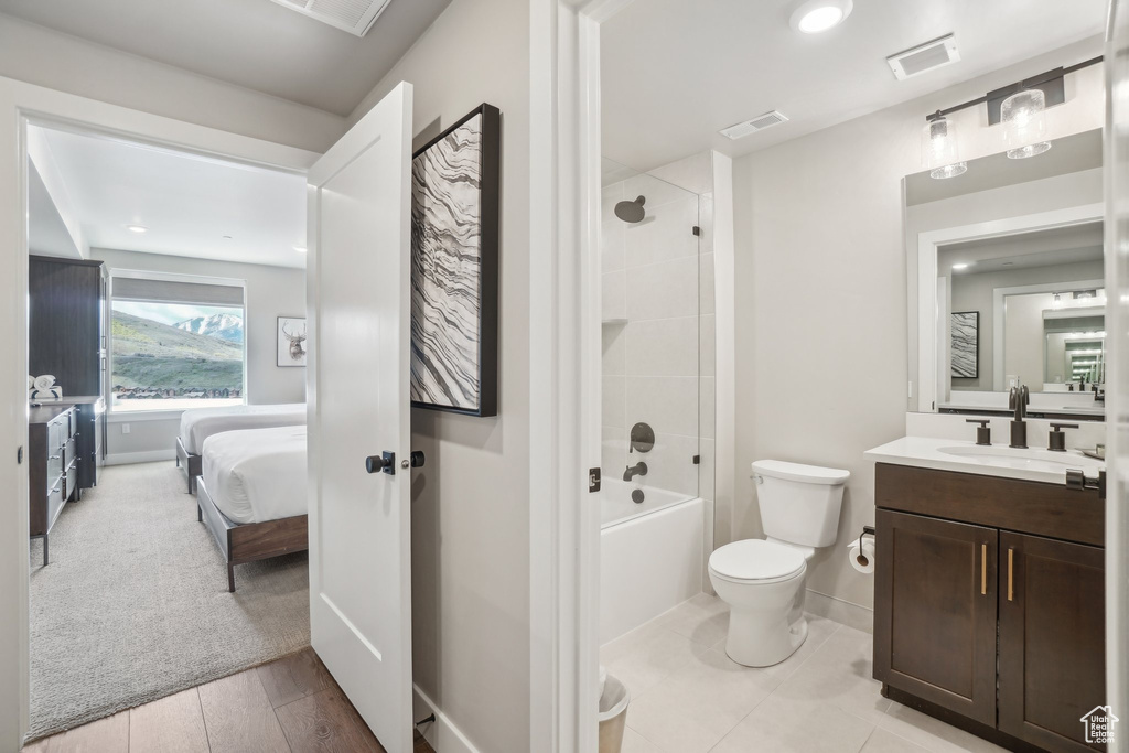 Ensuite bathroom featuring toilet, vanity, baseboards, and shower / bathtub combination