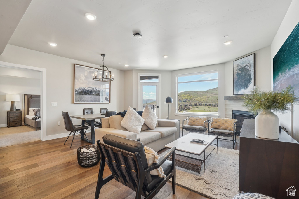 Living area featuring wood-type flooring, a chandelier, a glass covered fireplace, recessed lighting, and baseboards