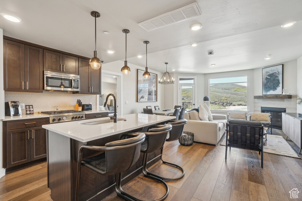 Kitchen featuring stainless steel microwave, a sink, open floor plan, dark brown cabinets, and wood-type flooring