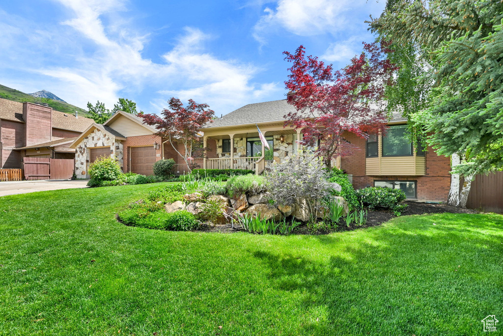 View of front facade featuring a garage, concrete driveway, a front lawn, and brick siding