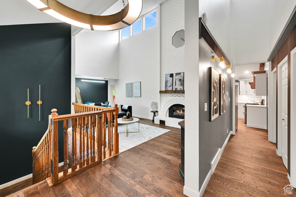 Corridor with an upstairs landing, a high ceiling, wood-type flooring, and baseboards