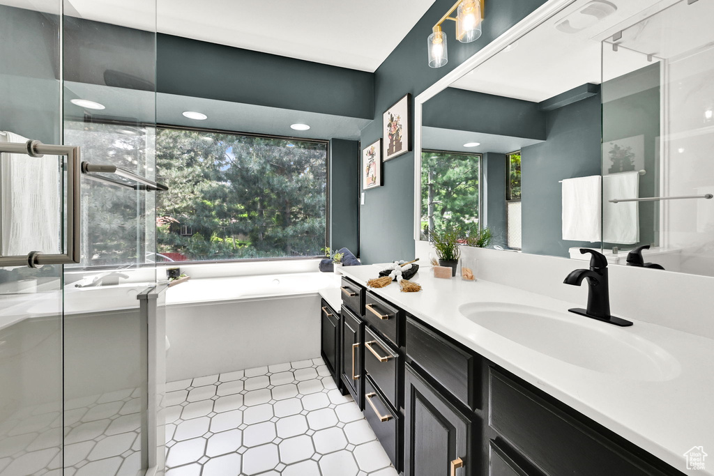 Full bath featuring tile patterned floors, healthy amount of natural light, a shower stall, and a bath