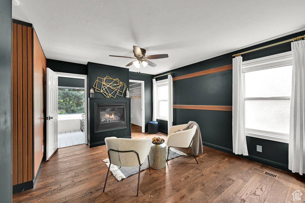 Living area with a glass covered fireplace, a ceiling fan, wood finished floors, and baseboards