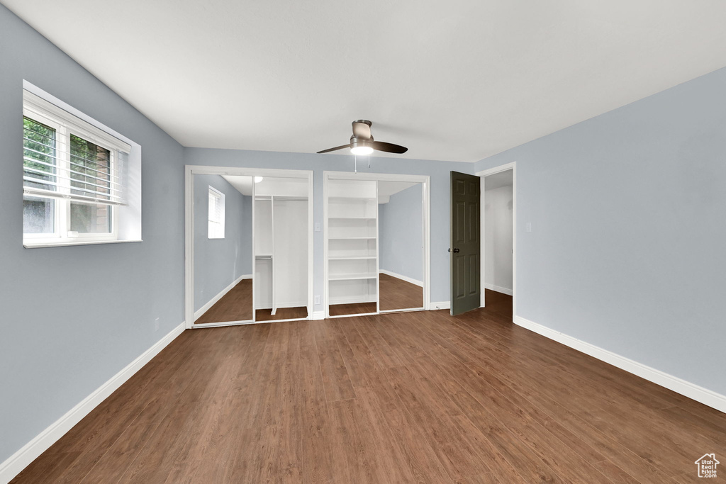 Unfurnished bedroom featuring dark wood-style flooring, baseboards, and ceiling fan