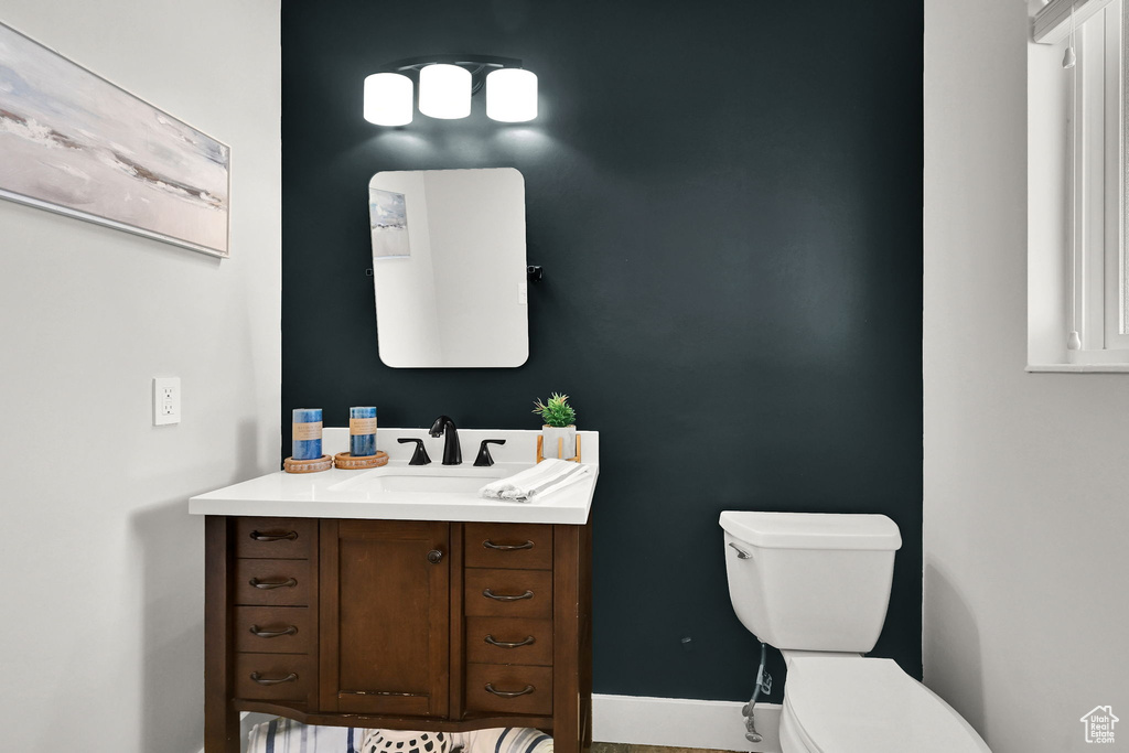 Half bath featuring toilet, vanity, and baseboards