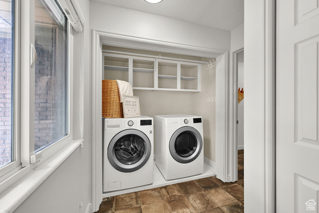 Washroom featuring washer and clothes dryer, dark stone finish flooring, and baseboards