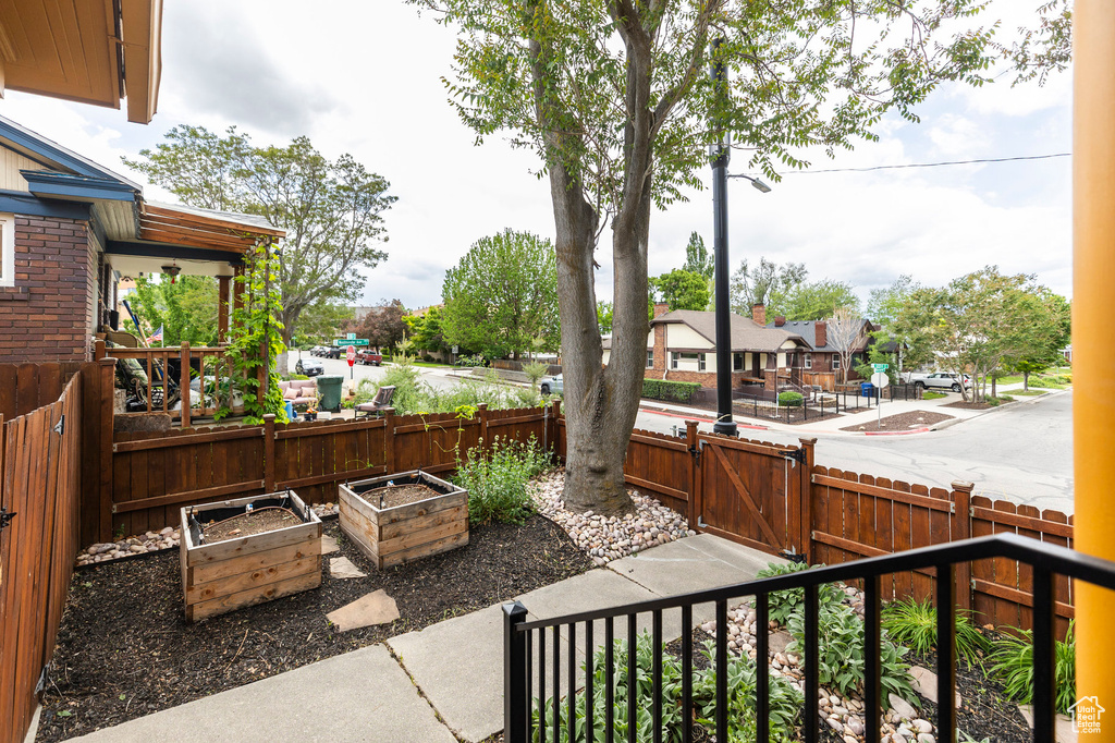 View of patio with a garden, a gate, and fence